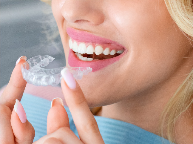 Mujer rubia se prueba sus alineadores invisibles (iFace, ClearCorrect) con una sonrisa.